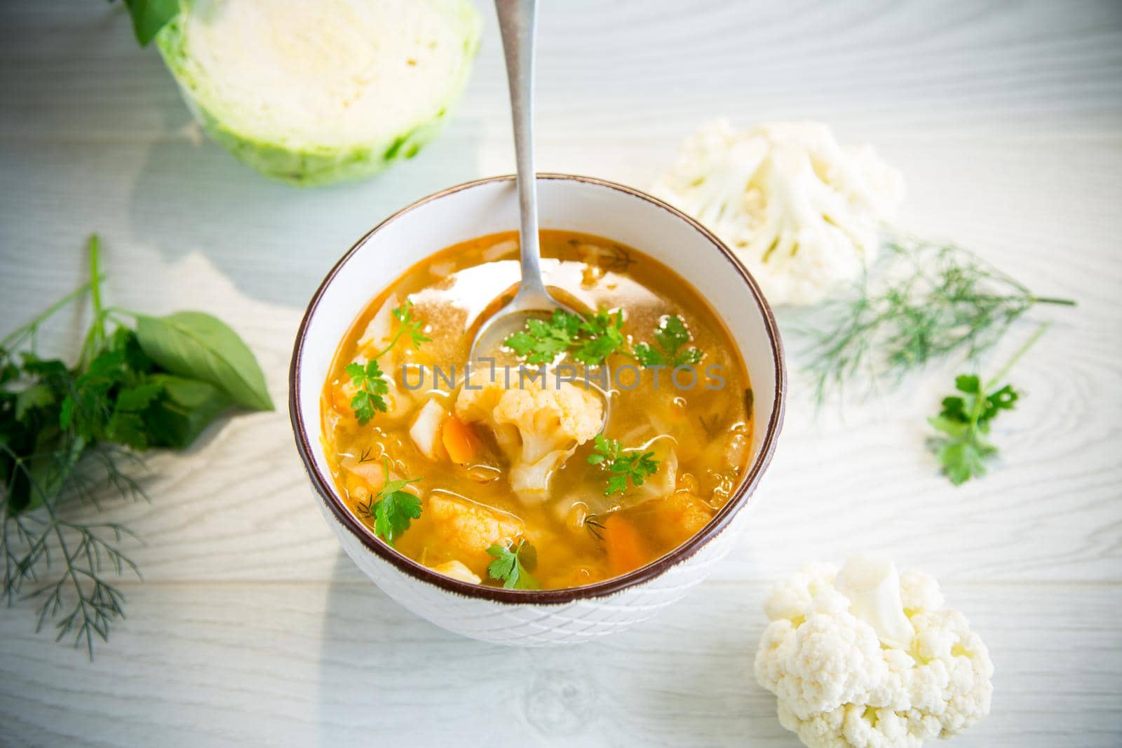 vegetable summer soup with cauliflower in a bowl on a light wooden table