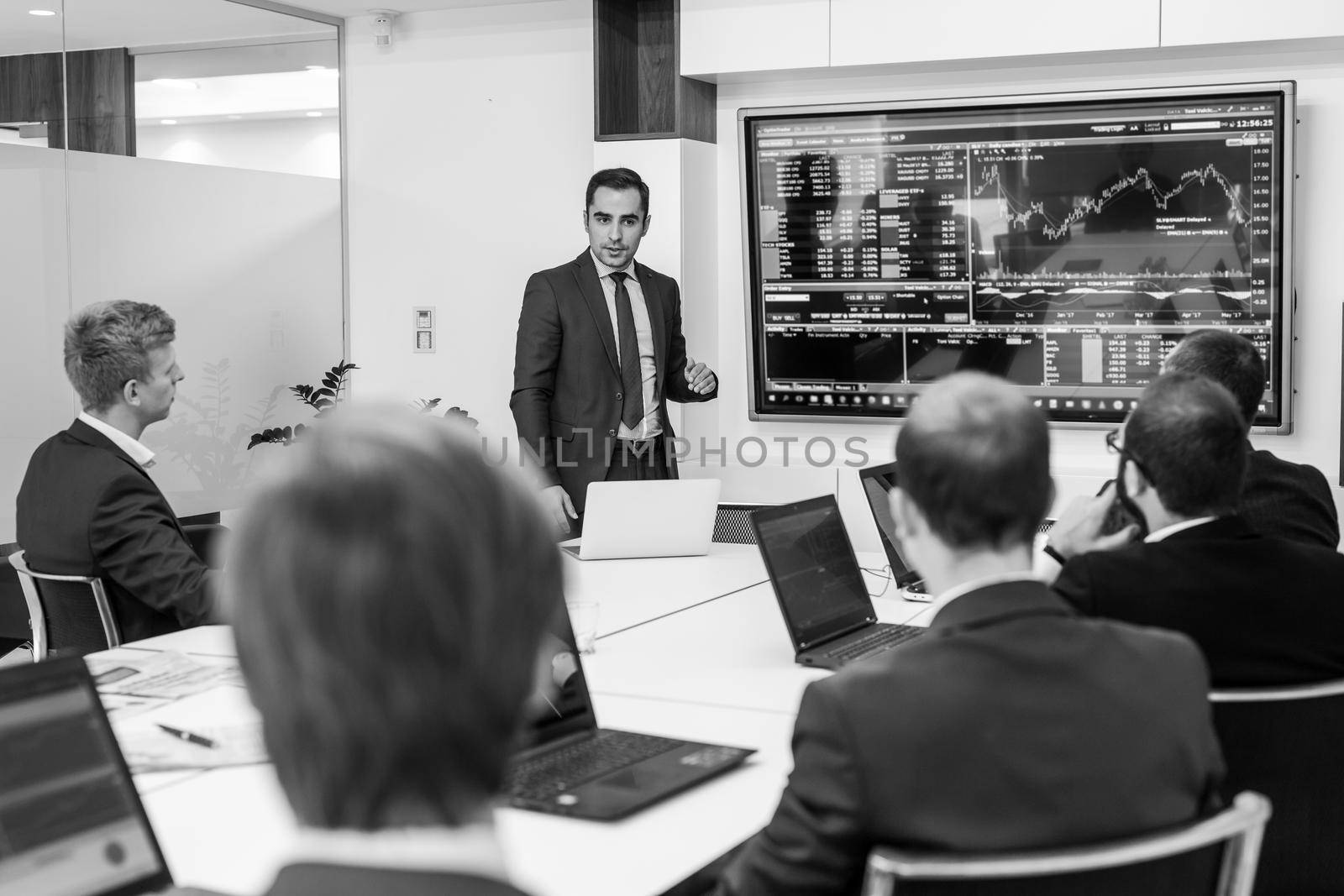 Business man making a presentation at office. Business executive delivering a presentation to his colleagues during meeting or in-house business training. Black and white image.