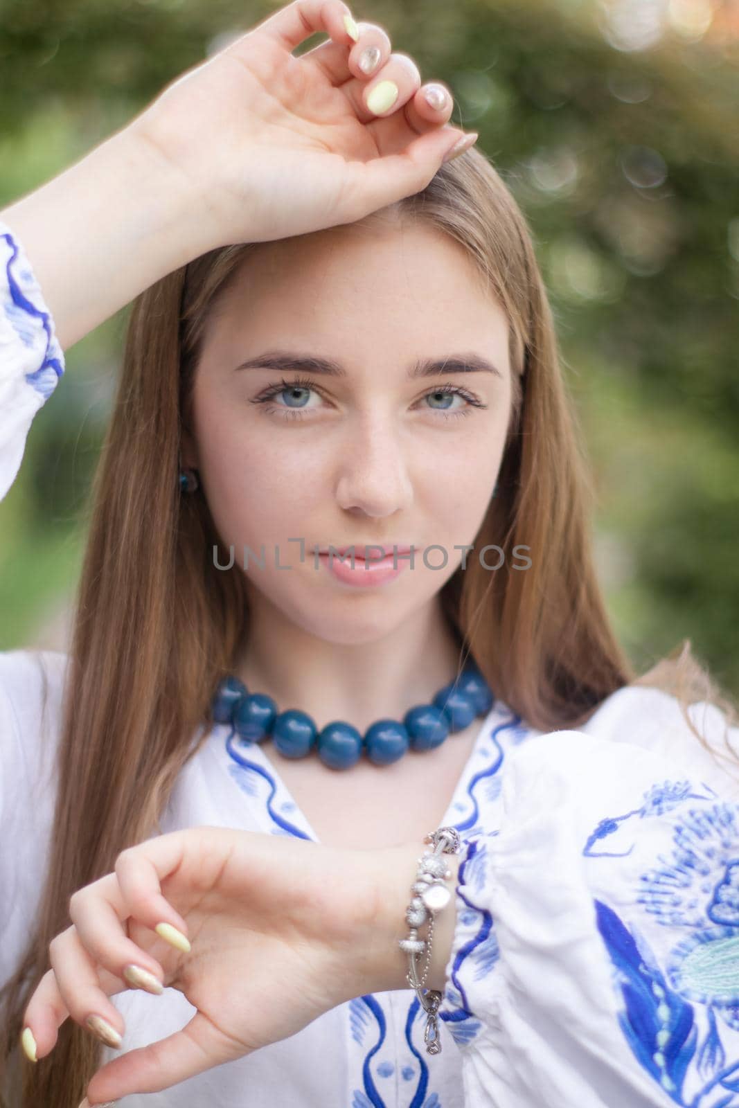 Portrait of young woman wearing blue national traditional embroidered shirt. pretty girl outdoor dressed in patriotic clothes.