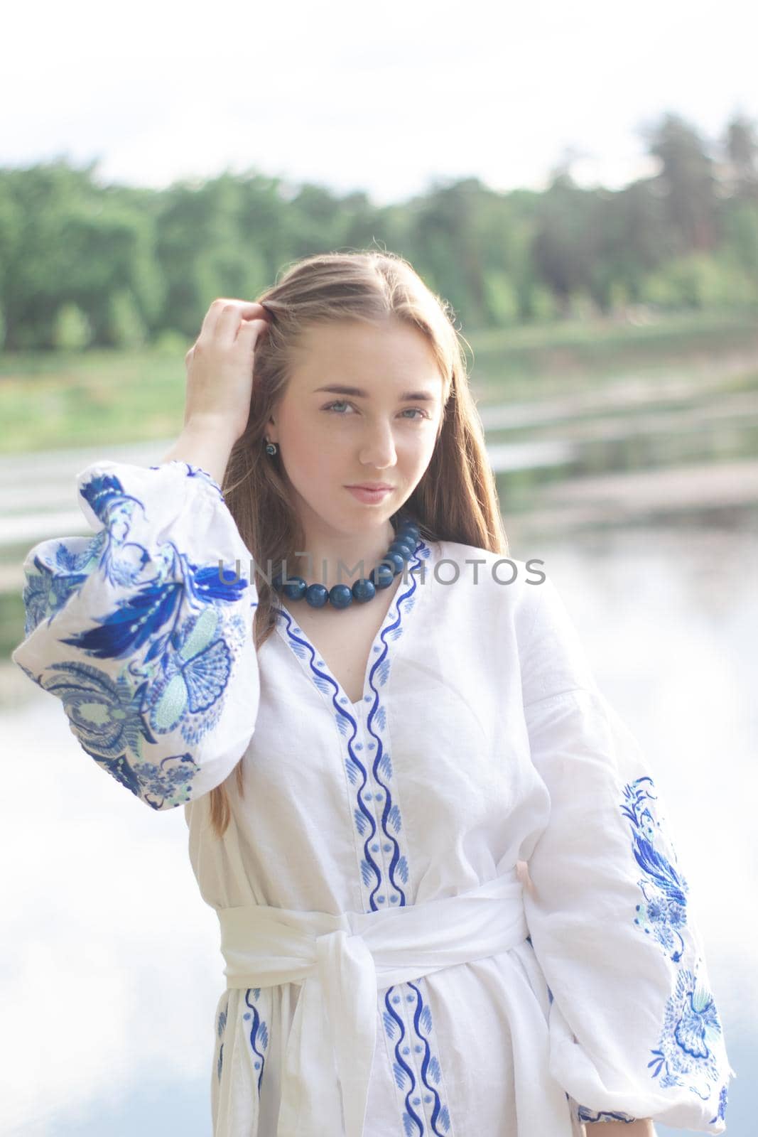 Portrait of young woman wearing blue national traditional embroidered shirt. pretty girl outdoor dressed in patriotic clothes.