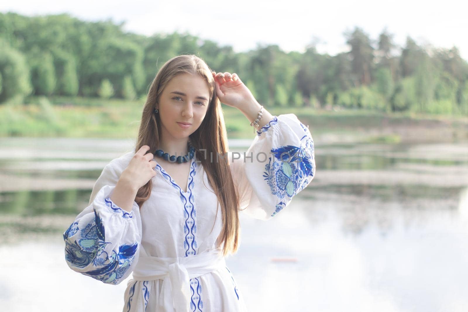 Portrait of young woman wearing blue national traditional embroidered shirt. pretty girl outdoor dressed in patriotic clothes.