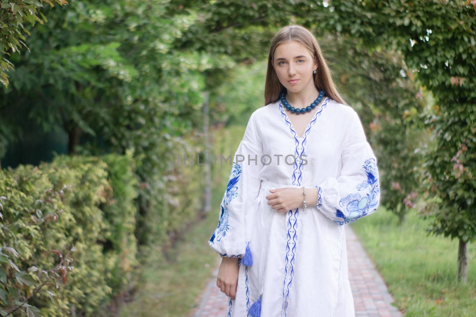 Portrait of young woman wearing blue national traditional embroidered shirt. pretty girl outdoor dressed in patriotic clothes by oliavesna