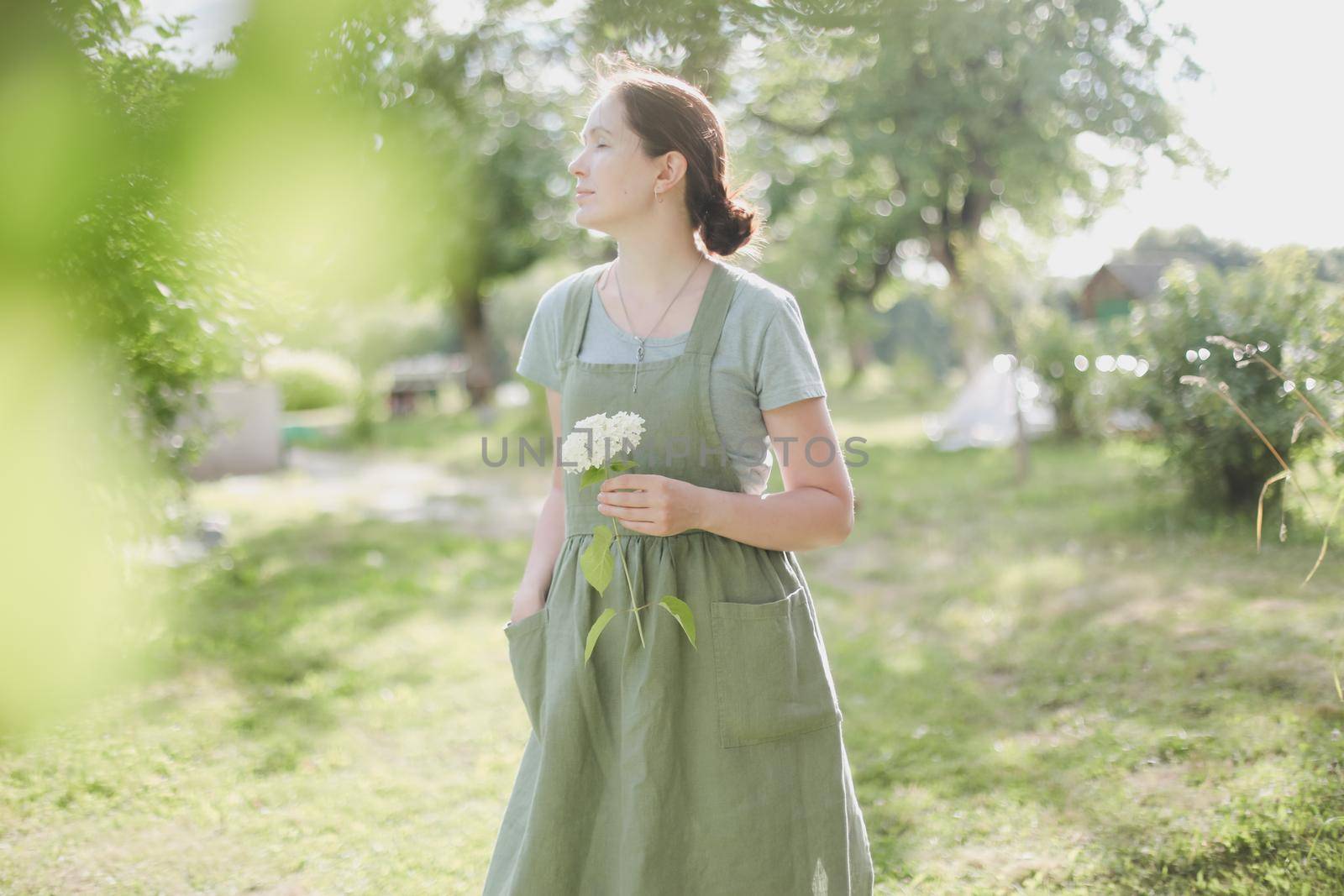 young woman in apron holding flowers in the garden in summer. gardening and profession concept