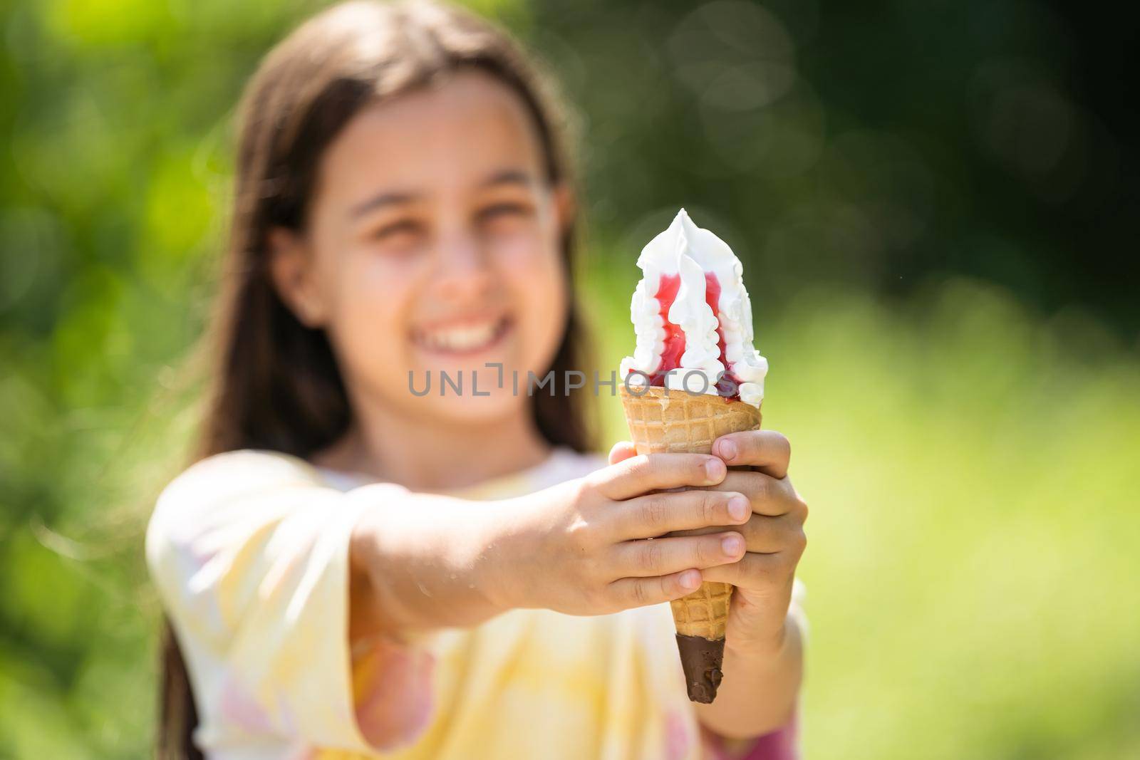 Beautiful little girl eats ice-cream in the summer.