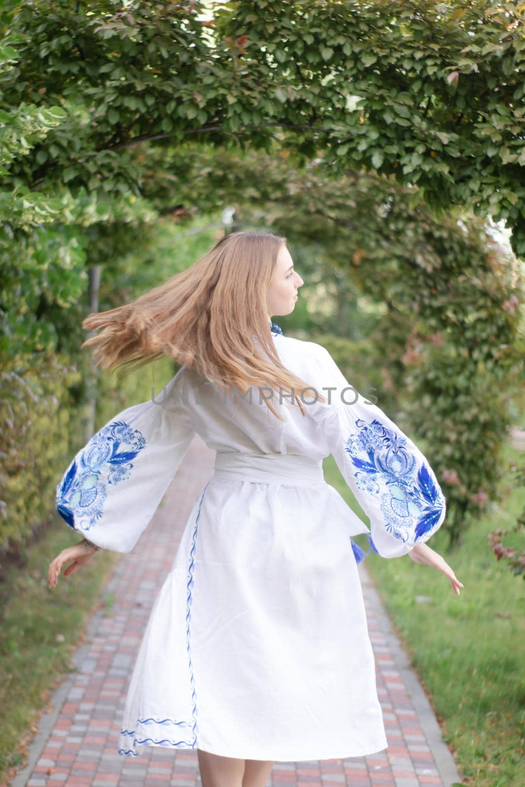 Portrait of young woman wearing blue national traditional embroidered shirt. pretty girl outdoor dressed in patriotic clothes by oliavesna