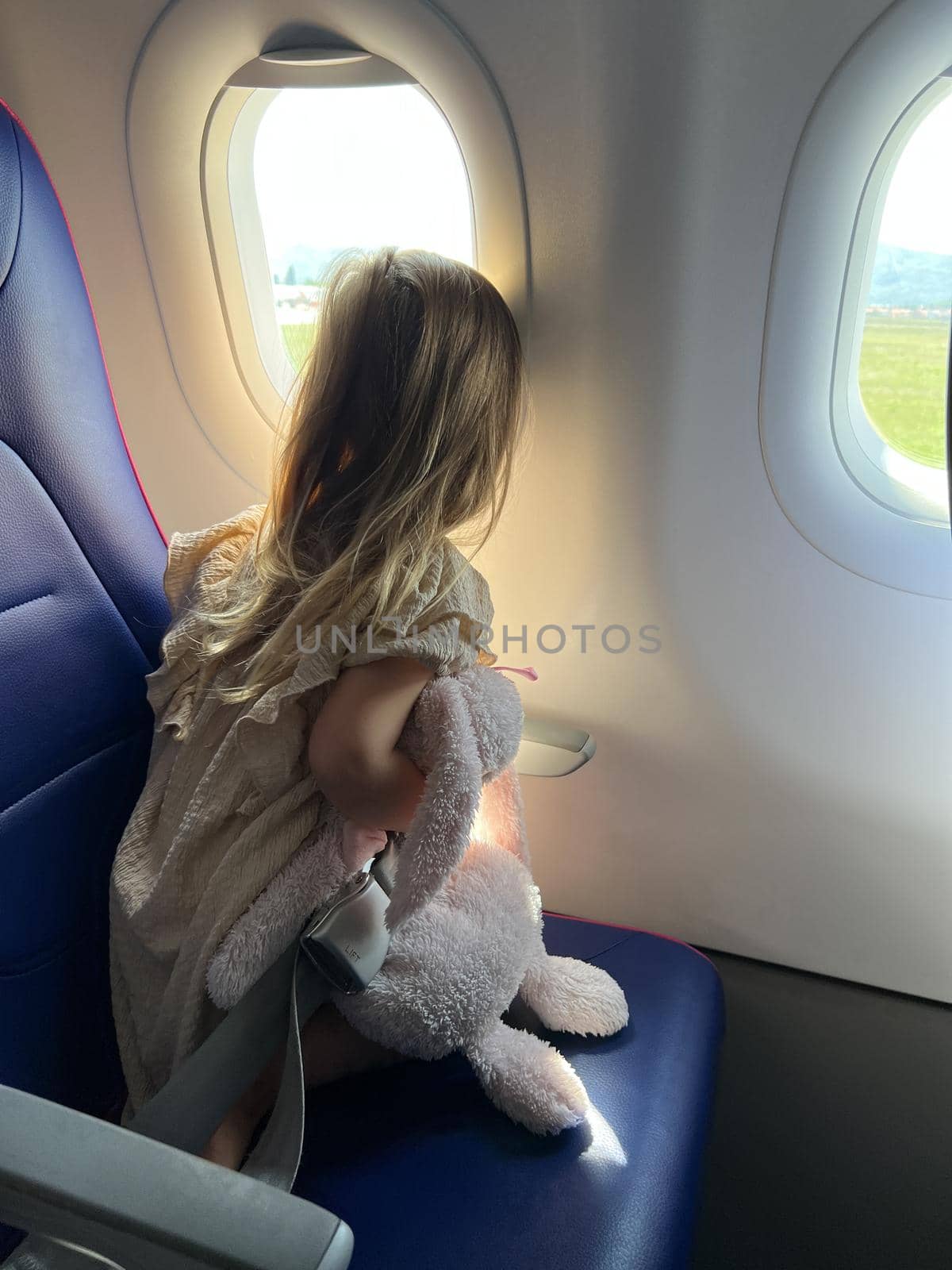 Little girl looks out the window of an airplane. Back view. High quality photo