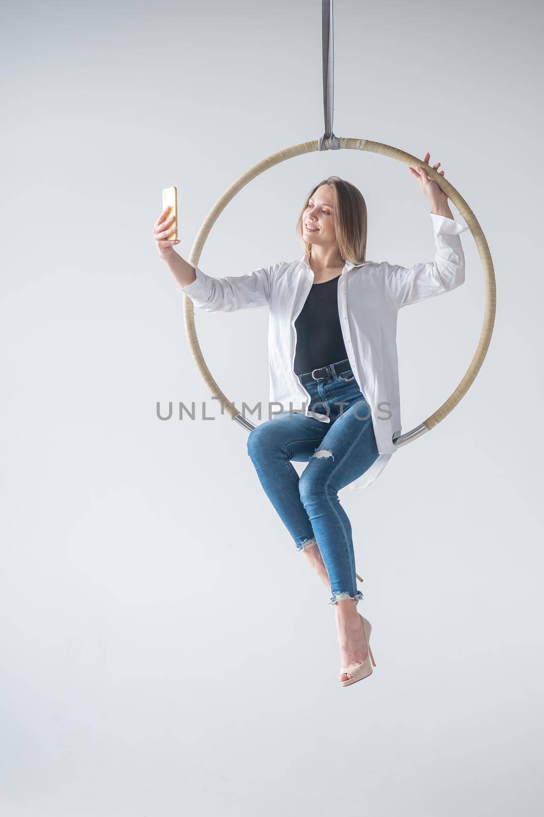 Caucasian woman gymnast on an aerial hoop takes a selfie on a smartphone