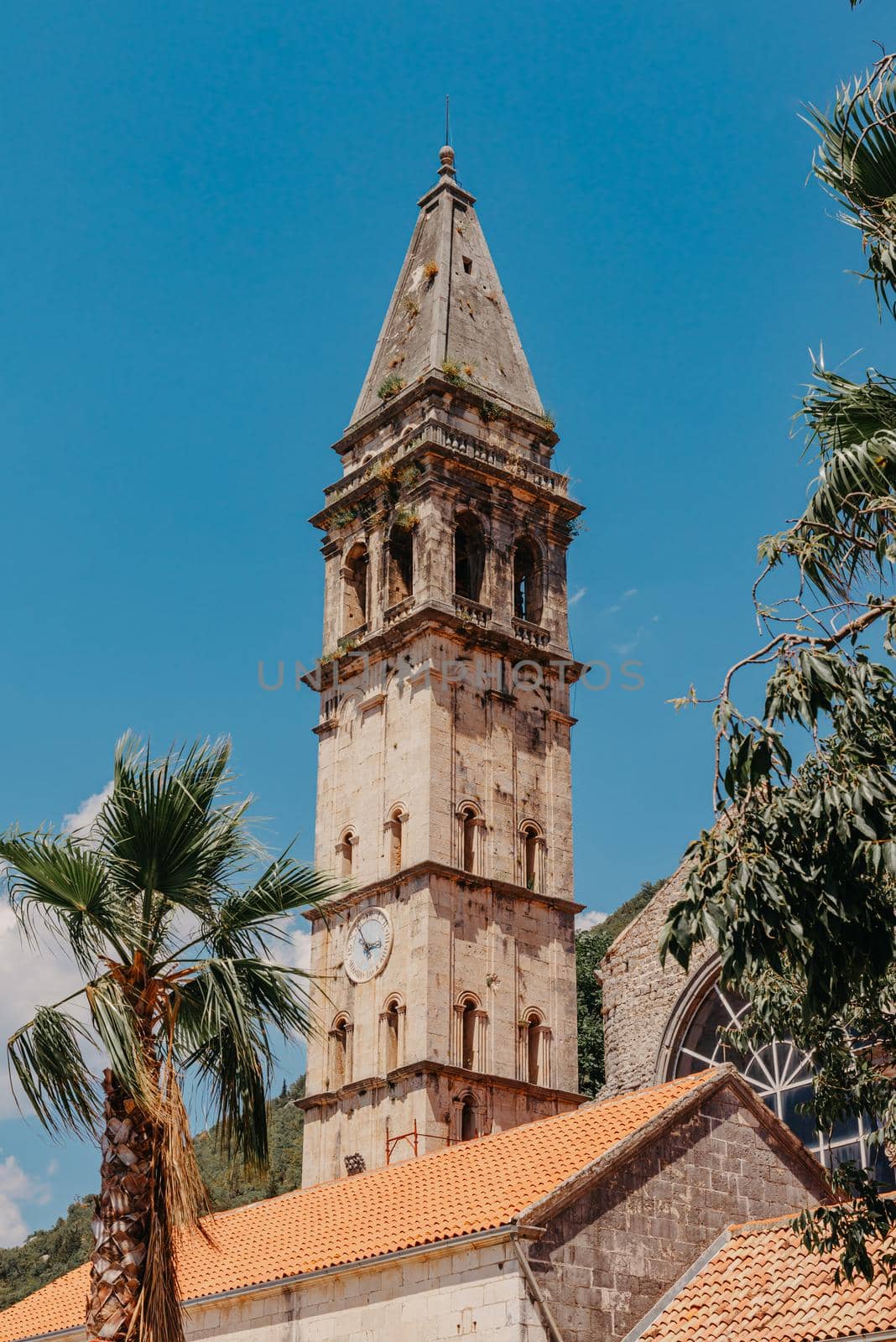 Historic city of Perast at Bay of Kotor in summer, Montenegro. Scenic panorama view of the historic town of Perast at famous Bay of Kotor with blooming flowers on a beautiful sunny day with blue sky and clouds in summer, Montenegro, southern Europe by Andrii_Ko