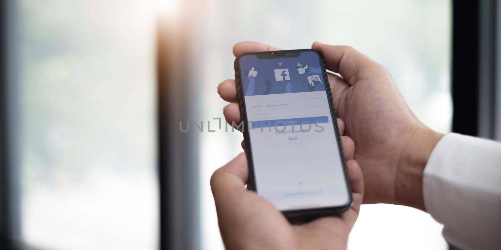 CHIANG MAI ,THAILAND JUL 13 2022 : Woman holding a iPhone X with social Internet service Facebook on the screen..