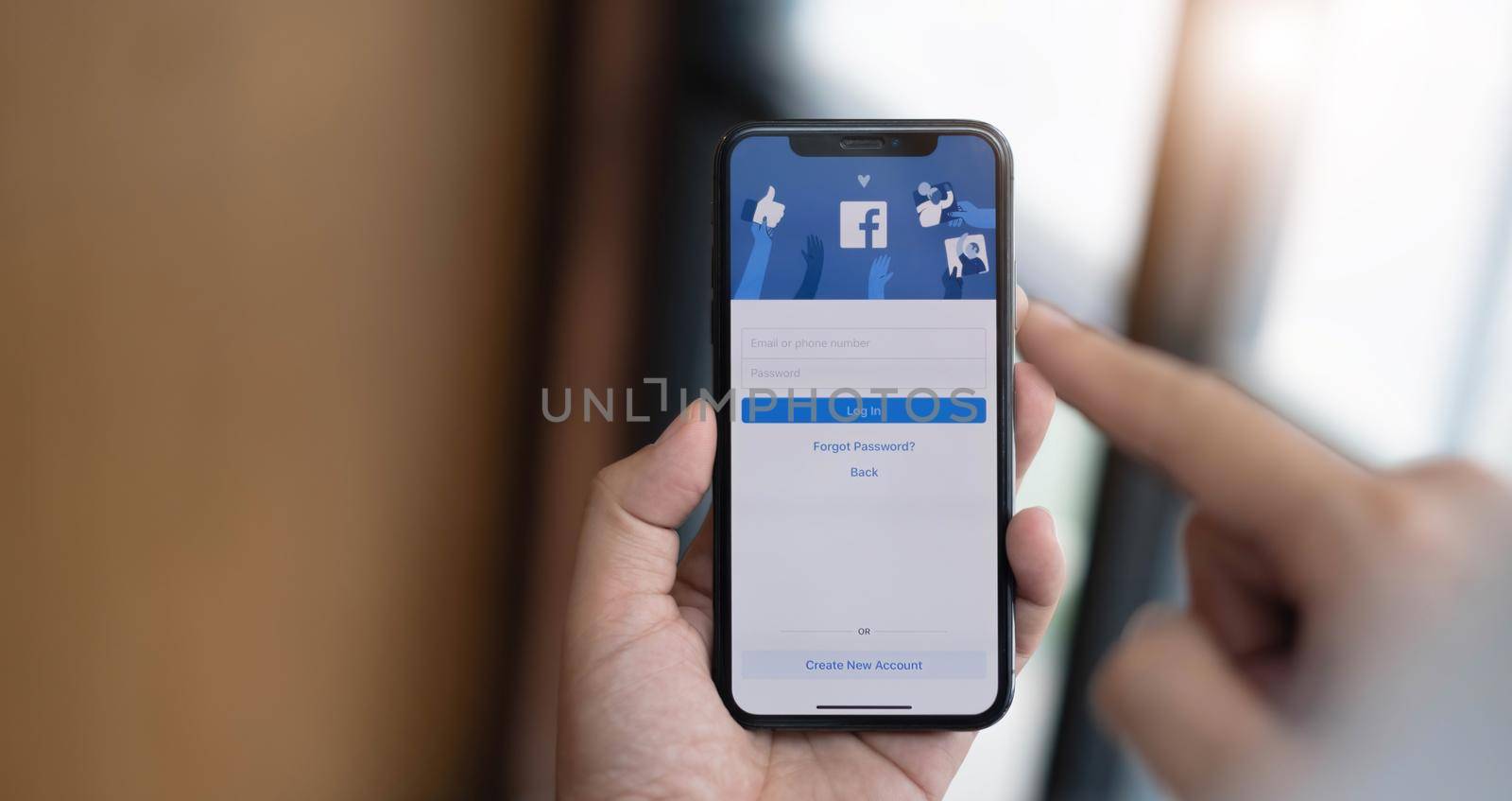CHIANG MAI ,THAILAND JUL 13 2022 : Woman holding a iPhone X with social Internet service Facebook on the screen. by wichayada