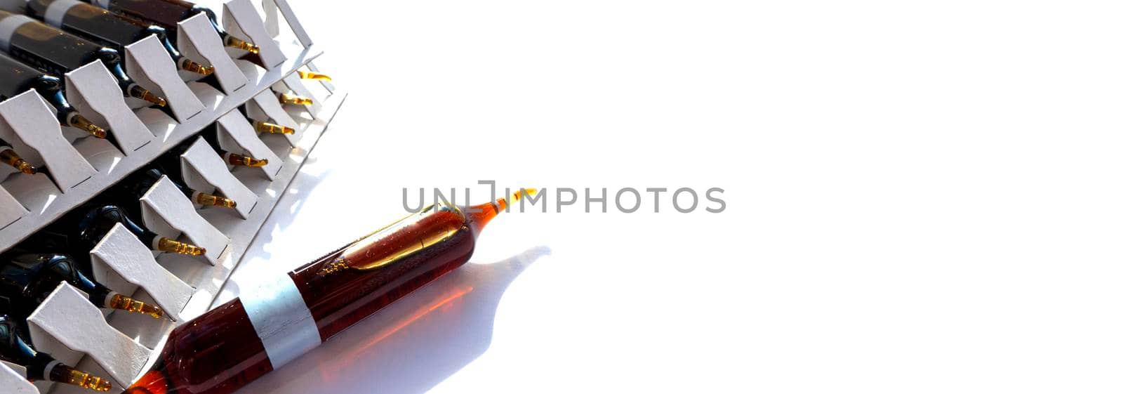 Group object of liquid medicinal agent in limpid glassware in medical laboratory. Group of ampoules with a transparent medicine in medical laboratory. horizontal perspective view of many brown ampoules set in pharmaceutical packaging white container