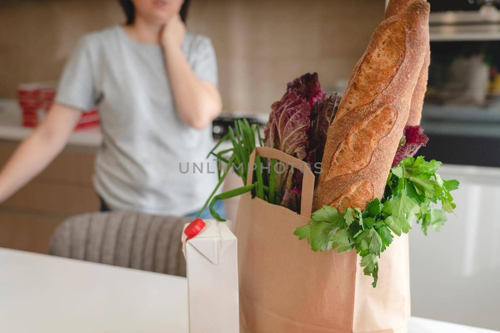 Paper bag with vegetables and bread, grocery with copy space with woman on background by Mariakray