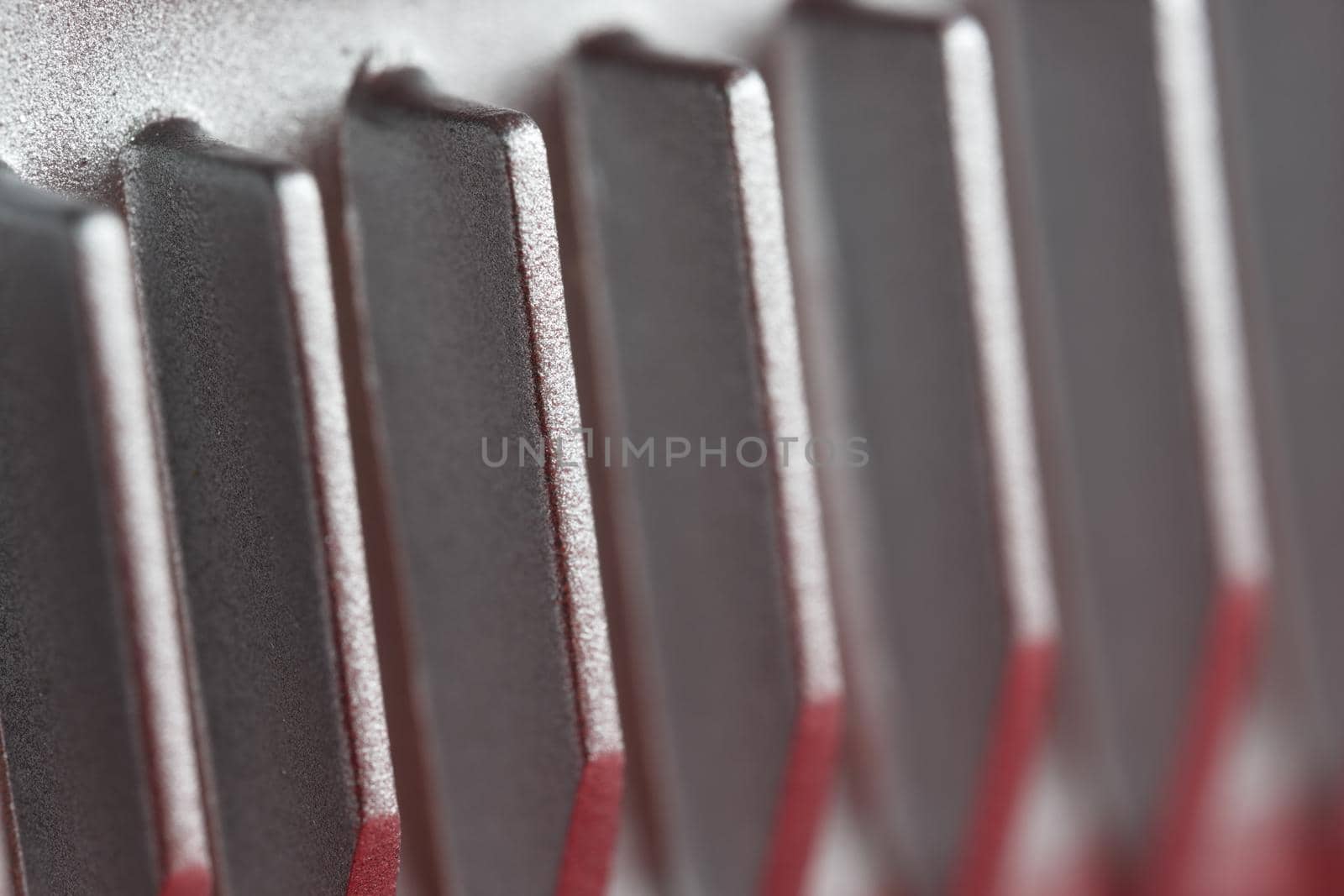 Aluminium or Aluminum heat sink cooling fins. Full frame super macro close up, showing metal detail and coarse finish. Red and silver color theme.