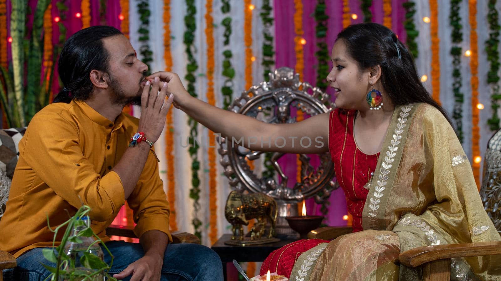 Indian families celebrating Raksha Bandhan festival a festival to celebrate the bond between brother and sister. Rakhi celebration in India. Feeding sweets, applying tikka.