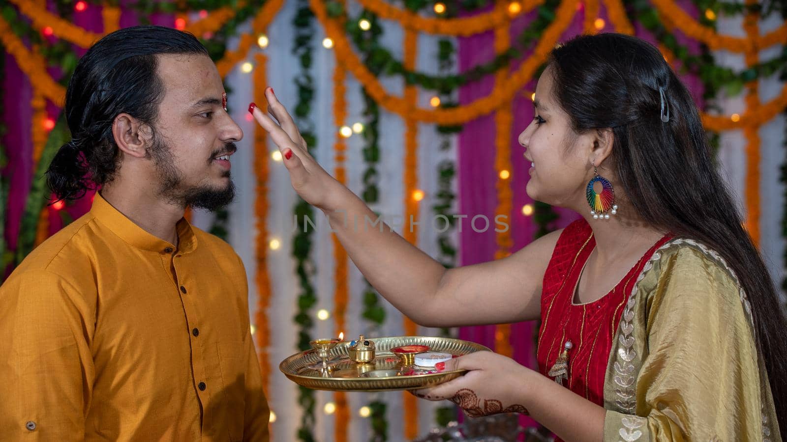 Indian families celebrating Raksha Bandhan festival a festival to celebrate the bond between brother and sister. Rakhi celebration in India. Feeding sweets, applying tikka.