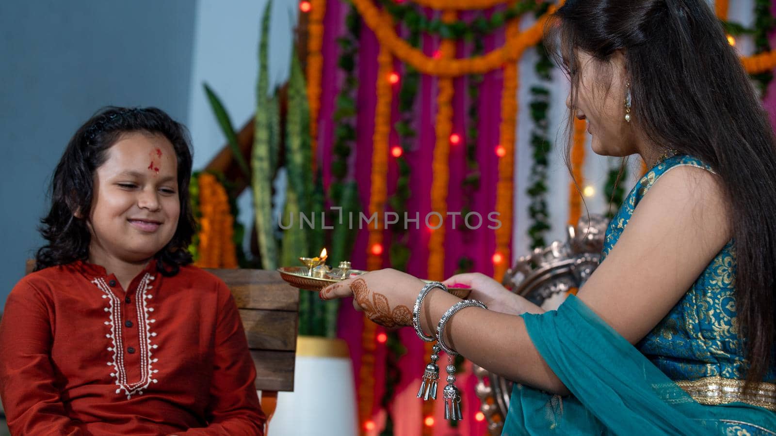 Indian families celebrating Raksha Bandhan festival a festival to celebrate the bond between brother and sister. Rakhi celebration in India. Feeding sweets, applying tikka.