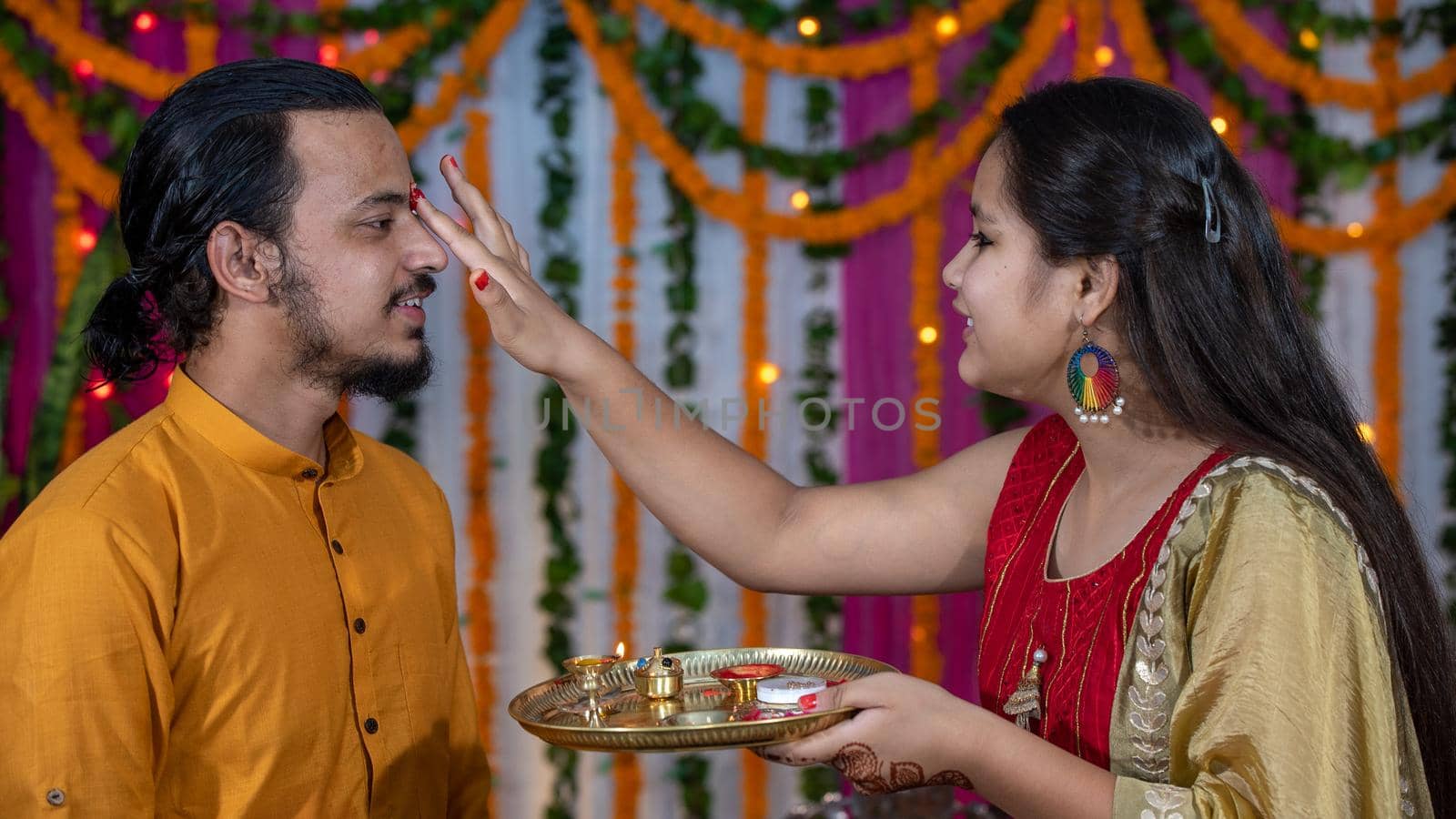 Indian families celebrating Raksha Bandhan festival a festival to celebrate the bond between brother and sister. Rakhi celebration in India. Feeding sweets, applying tikka.