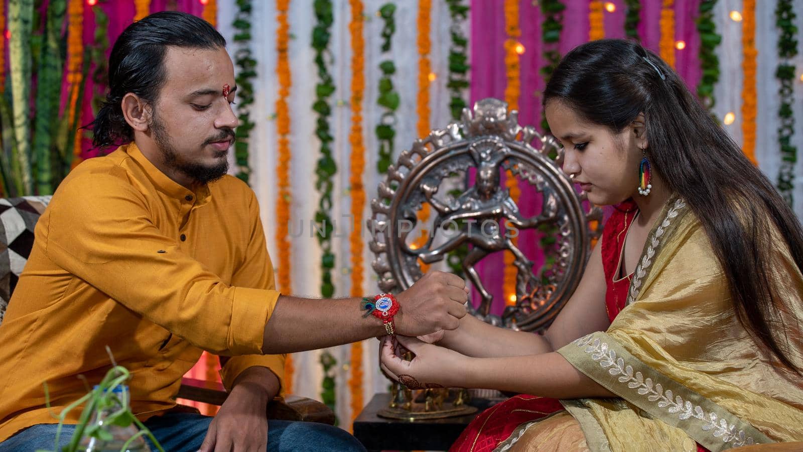 Sister tying the rakhi, Raksha Bandhan to brother's wrist during festival or ceremony - Raksha Bandhan celebrated across India as selfless love or relationship between brother and sister