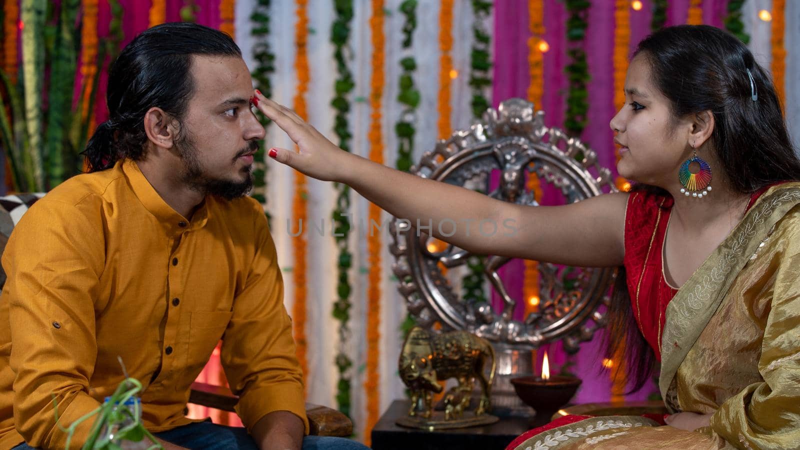 Indian families celebrating Raksha Bandhan festival a festival to celebrate the bond between brother and sister. Rakhi celebration in India. Feeding sweets, applying tikka.