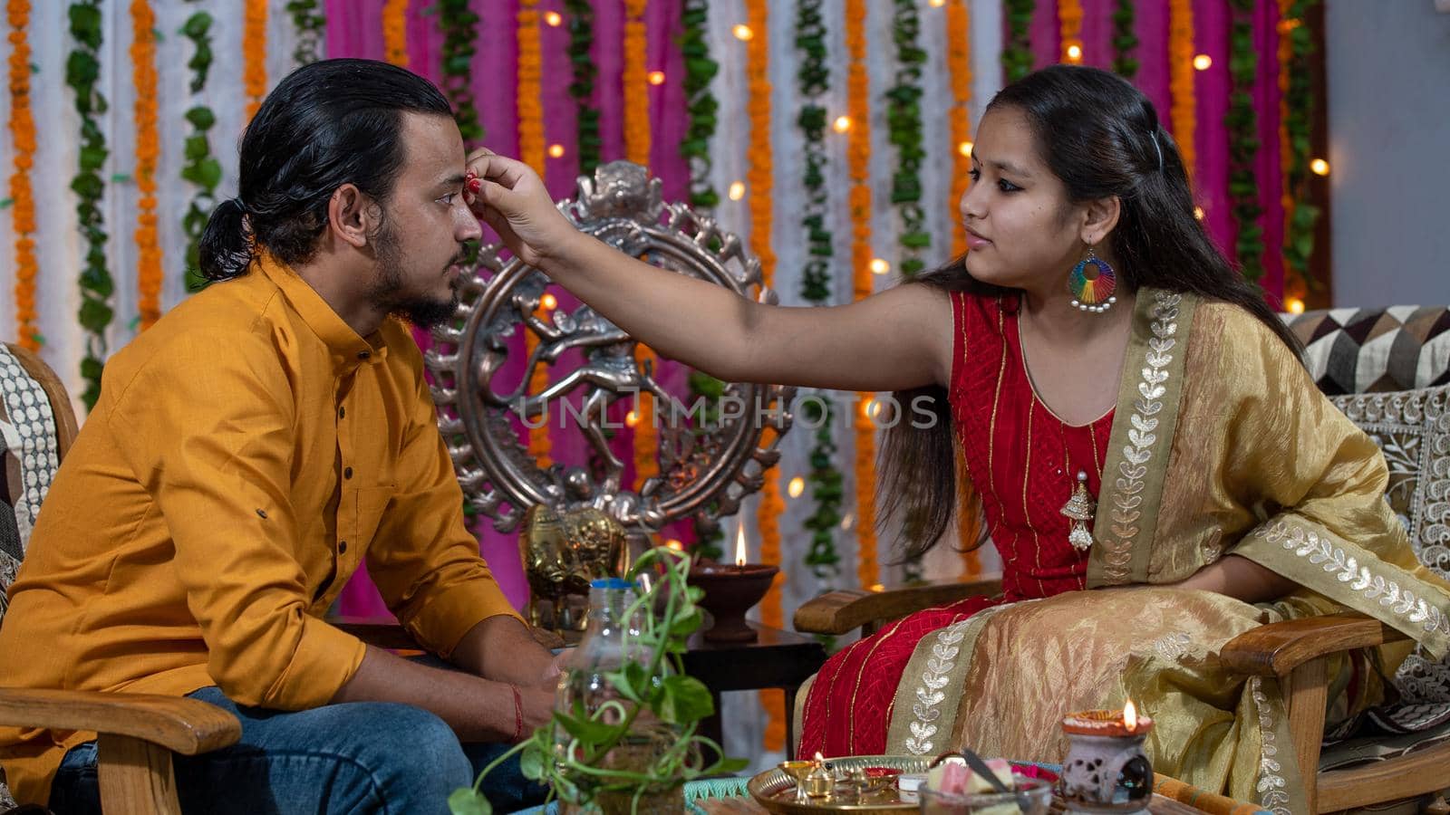 Indian families celebrating Raksha Bandhan festival a festival to celebrate the bond between brother and sister. Rakhi celebration in India. Feeding sweets, applying tikka.