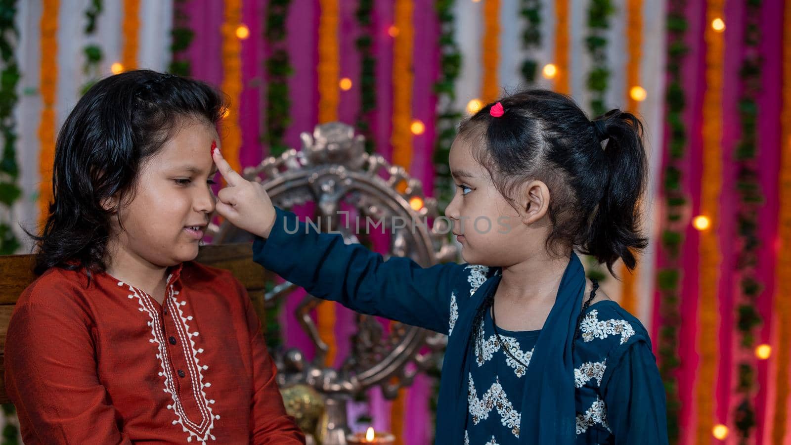 Indian families celebrating Raksha Bandhan festival a festival to celebrate the bond between brother and sister. Rakhi celebration in India. Feeding sweets, applying tikka.