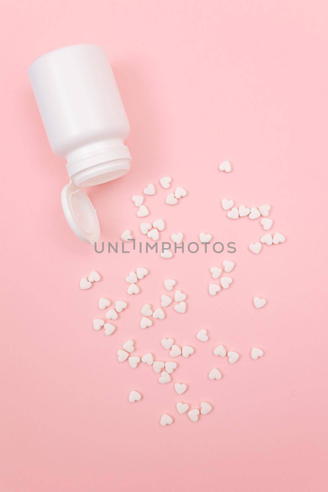 Global Pharmaceutical Industry and Medicinal Products - White Pills or Tablets Scattered from the Pill Container, Lying on Pink Background