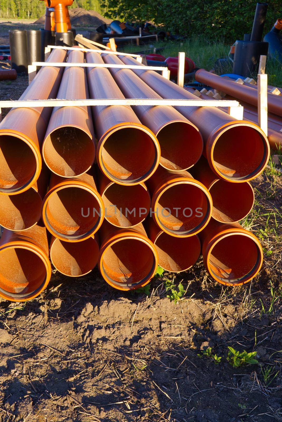 sewer orange pvc pipes stacked on construction site. plumbing plastic pipes.