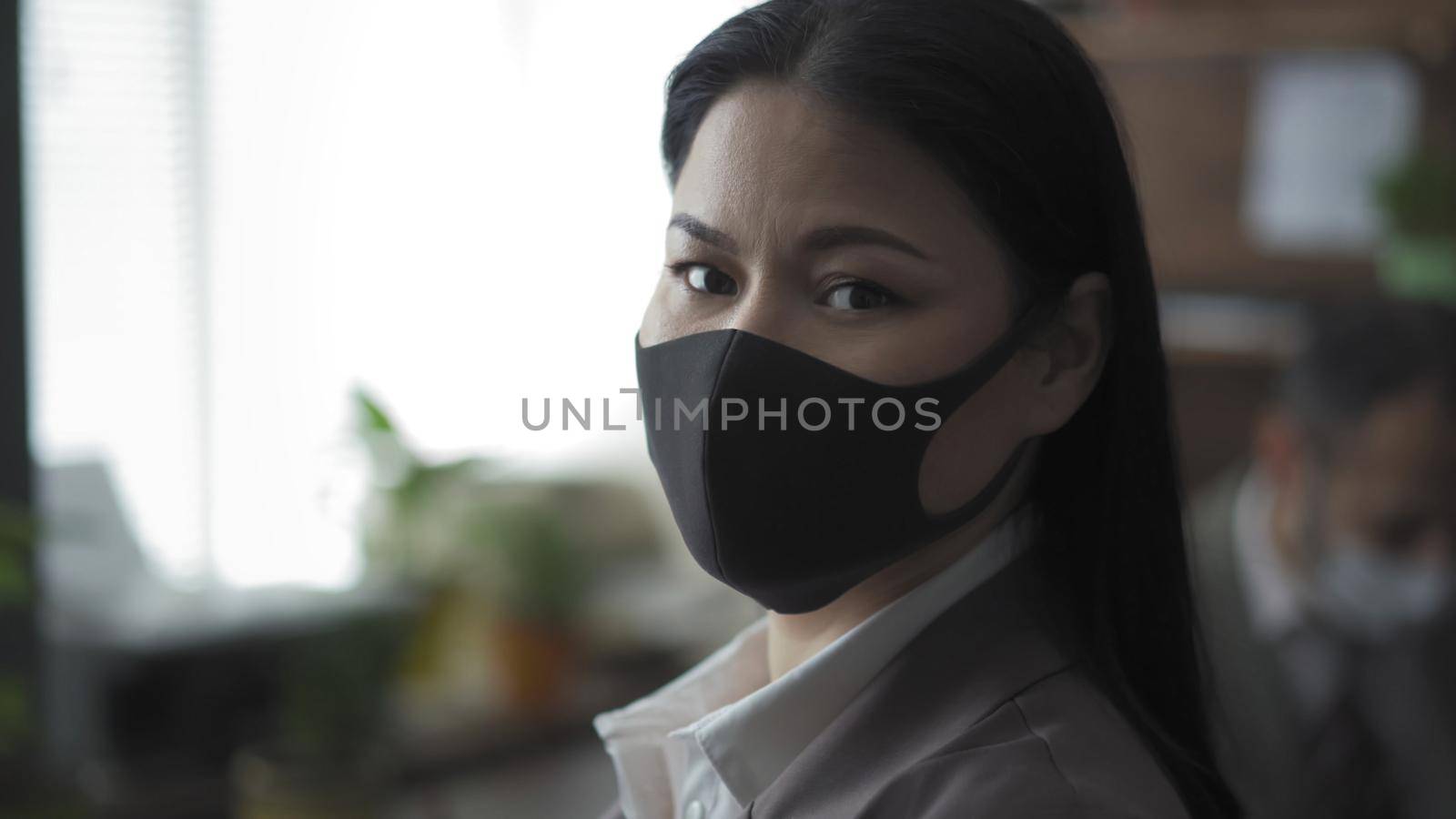 Young Woman In Protective Mask Works In Office by LipikStockMedia