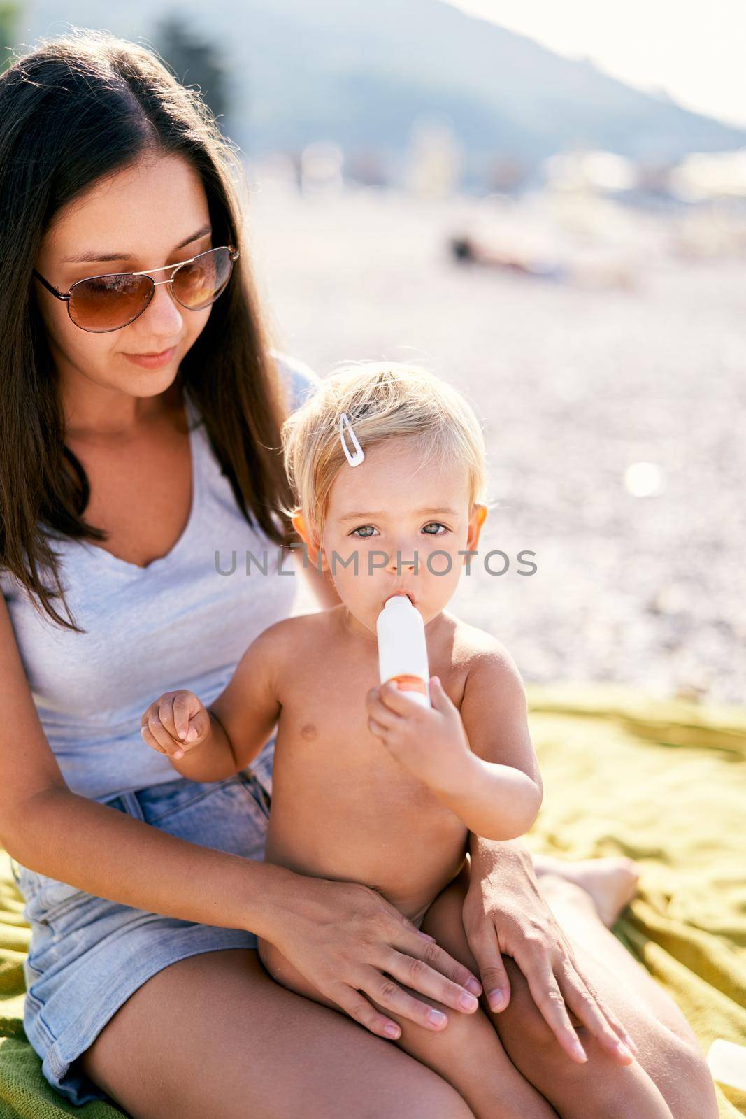 Little girl in her mother arms eats baby formula from a bottle. High quality photo