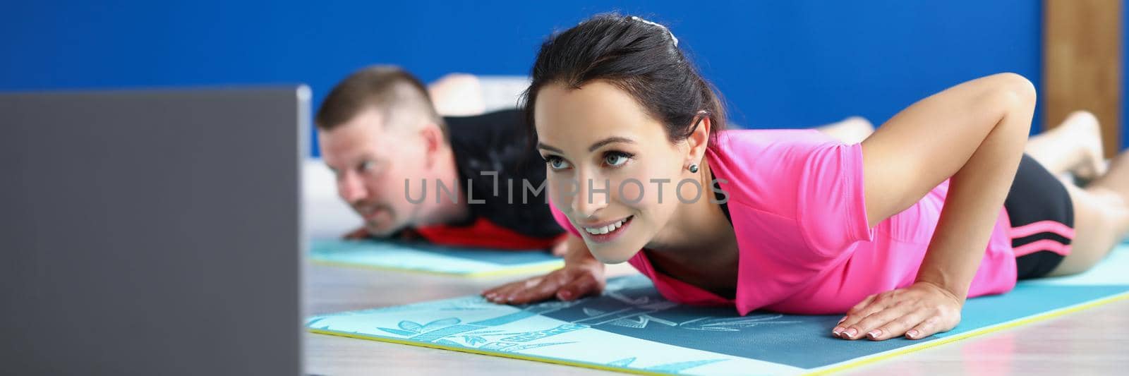 Low angle of woman and man practicing yoga in studio, perform asana on mat. Morning ritual for body and soul health. Active lifestyle, hobby, habit concept