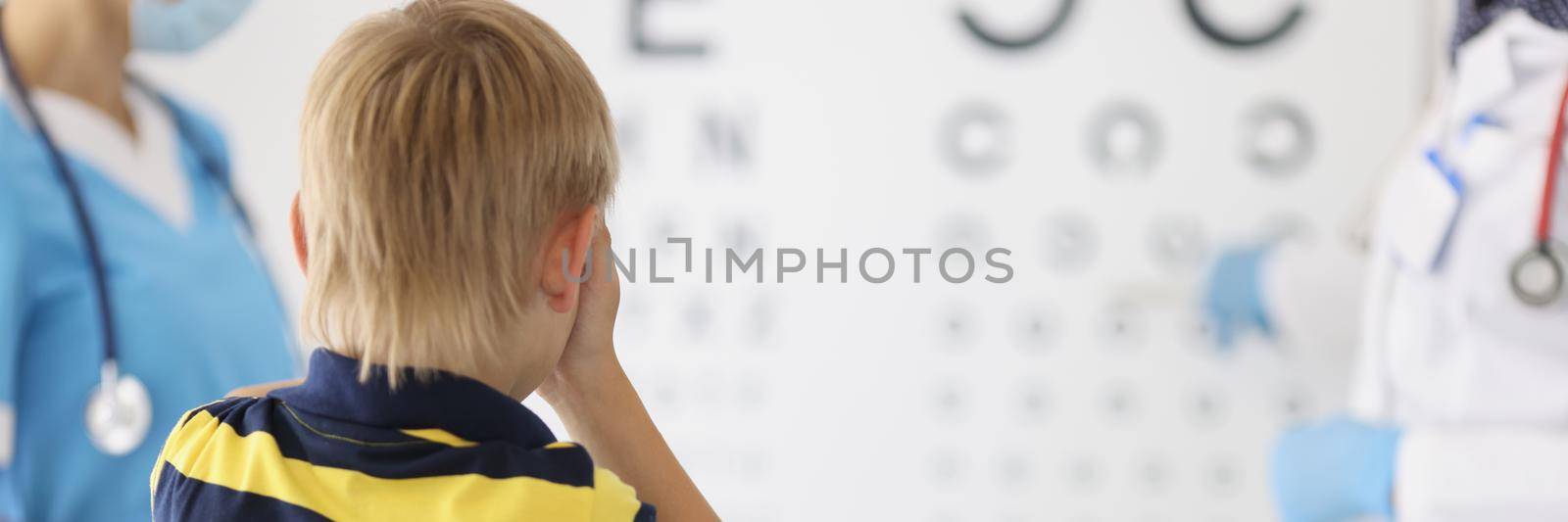 Little boy on appointment at oculist office, check sight closing eye by kuprevich