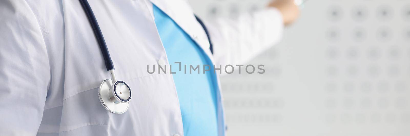 Close-up of female eye doctor point on letter on eye test chart. Optician in uniform, appointment in eye clinic. Checkup, health, ophthalmologist concept