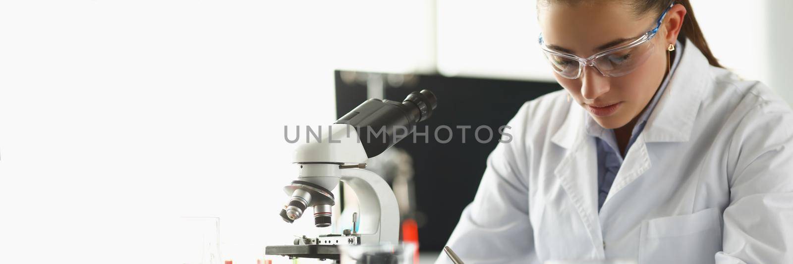 Portrait of concentrated chemist worker write down thoughts on investigation project in lab. Biologist examine samples in modern clinic. Science concept