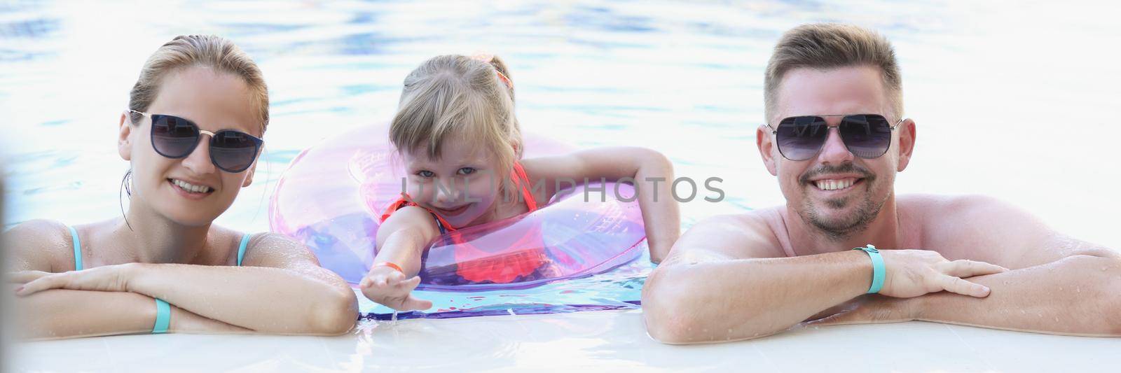 Portrait of happy family posing for picture together in swimming pool. Memorable vacation in luxury resort, family holiday. Summer, childhood, trip concept