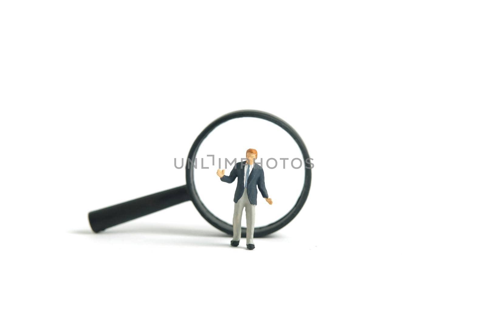 Miniature people toy figure photography. A shrugging businessman finding solution standing in front of magnifier glass. Isolated on white background. Image photo
