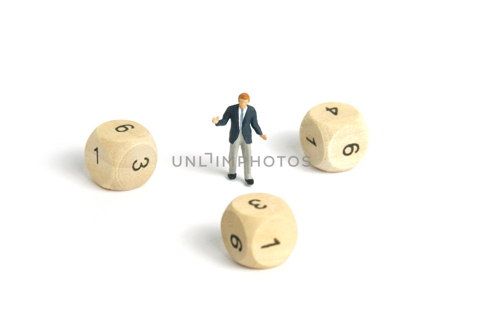 Miniature people toy figure photography. A shrugging businessman standing in the middle of wooden dice. Isolated on white background. Image photo
