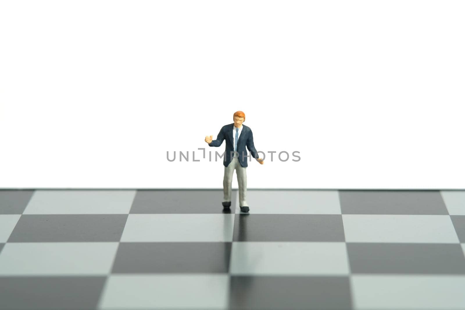 Miniature people toy figure photography. Strategy decision concept. A shrugging unsure businessman stand above chessboard. Isolated on white background. Image photo