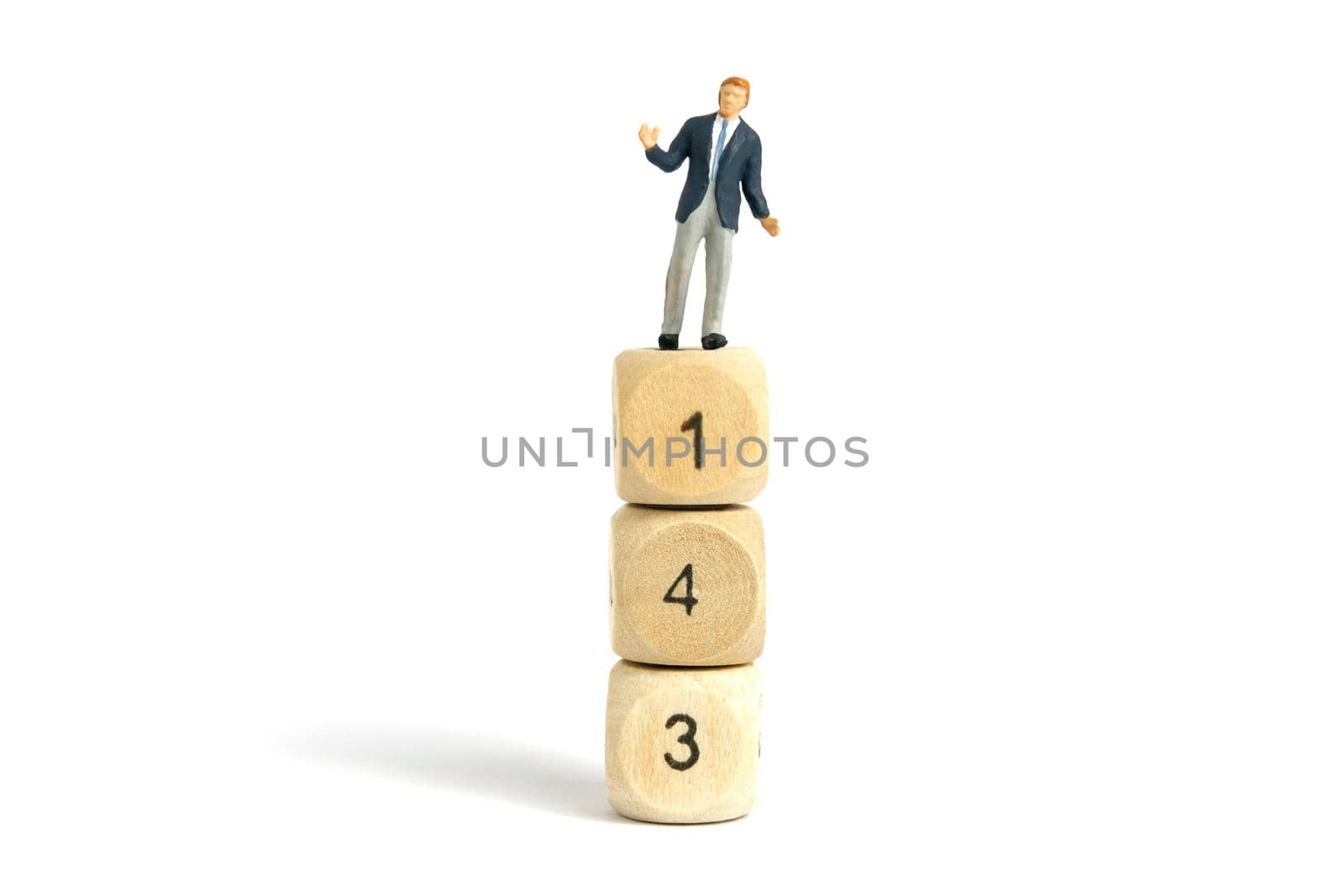 Miniature people toy figure photography. A shrugging businessman standing above wooden dice. Isolated on white background. Image photo