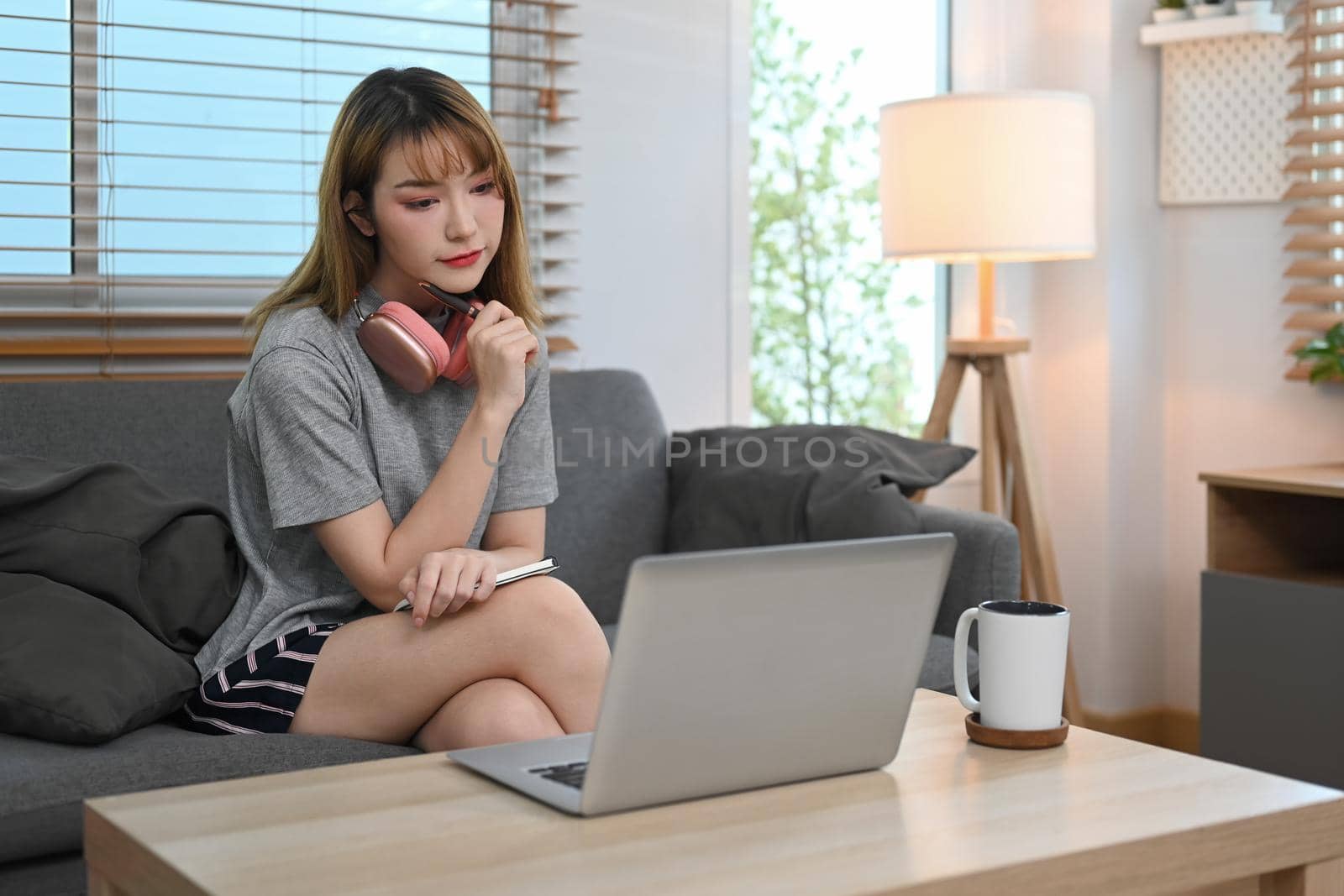 Beautiful young woman browsing internet on computer, reading online news on weekend.