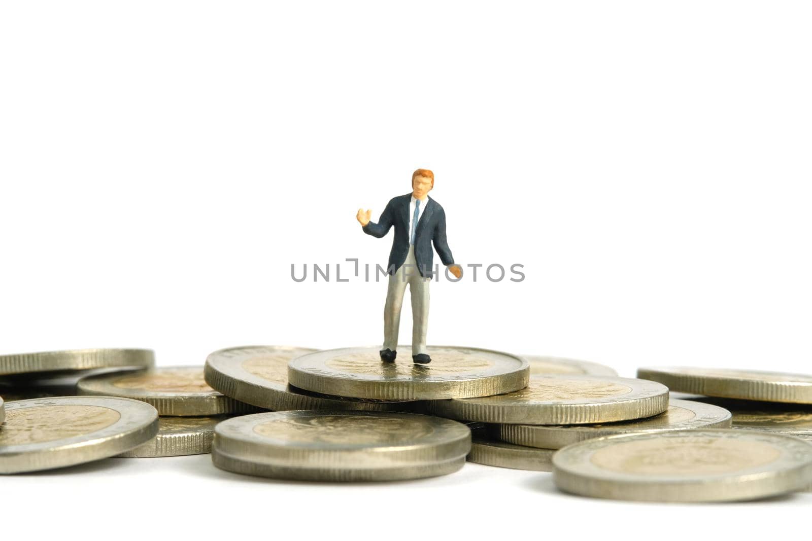 Miniature people toy figure photography. Financial plan concept. A shrugging businessman stand above coin money pile. Isolated on white background. Image photo