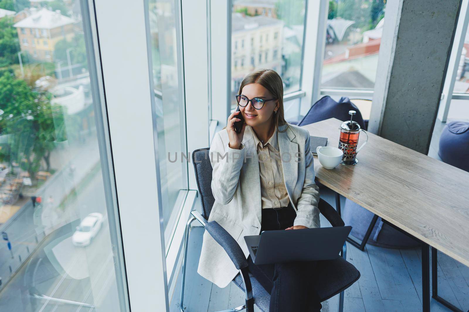 Smiling business woman looking at laptop while working in office. The concept of a modern successful woman. The idea of business and life of an entrepreneur. Young woman at table with open laptop