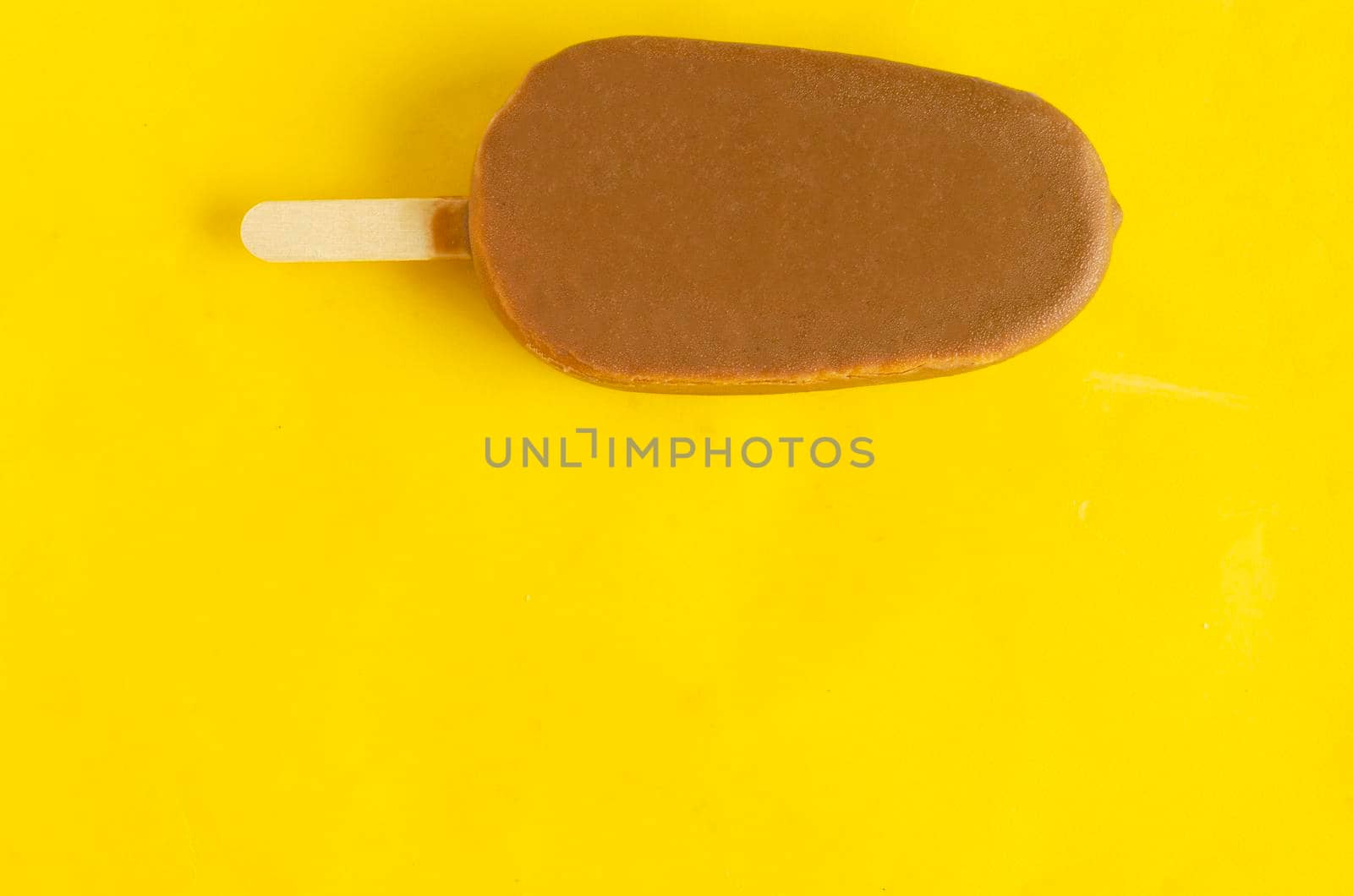 Banana vanilla popsicle in chocolated glaze on bright yellow background,copyspace. by andre_dechapelle