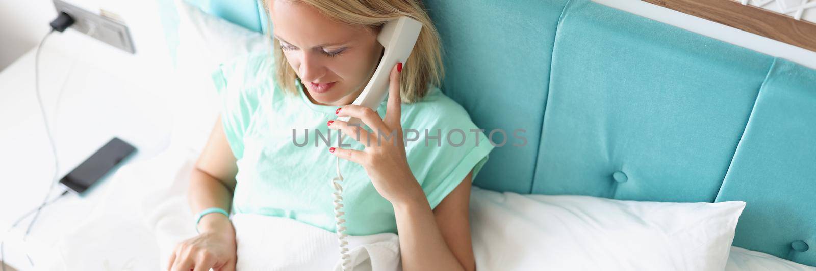Top view of young woman calling on reception in hotel to order breakfast in room. Female enjoy luxury service on resort. Holiday, chill, lunch time concept