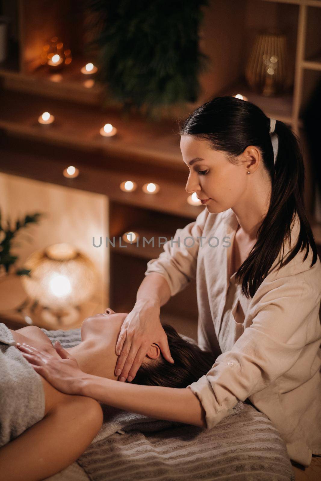 A cosmetologist girl does a facial and neck massage to a girl in the office for skin elasticity.