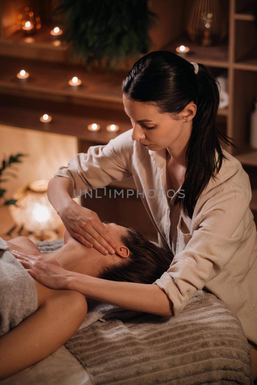 A cosmetologist girl does a facial and neck massage to a girl in the office for skin elasticity.