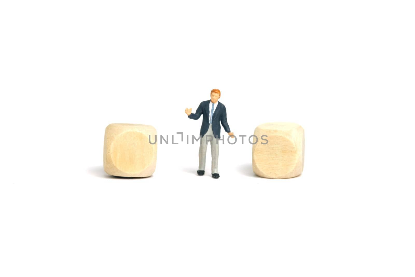 Miniature people toy figure photography. A shrugging businessman standing in the middle of two blank wooden dice. Isolated on white background. Image photo by Macrostud