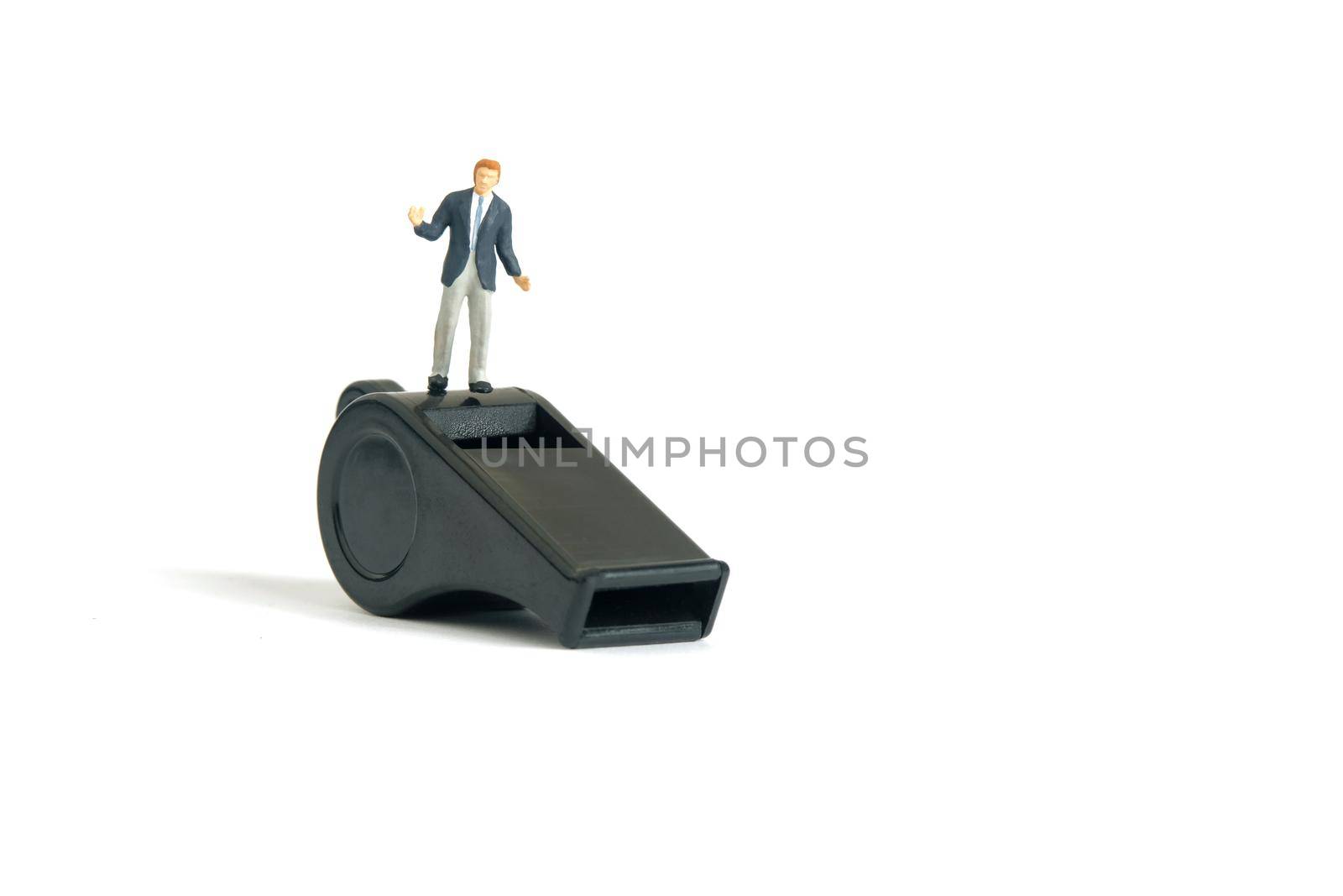 Miniature people toy figure photography. Whistle blower concepts. A shrugging businessman standing above black whistle. Isolated on white background. Image photo