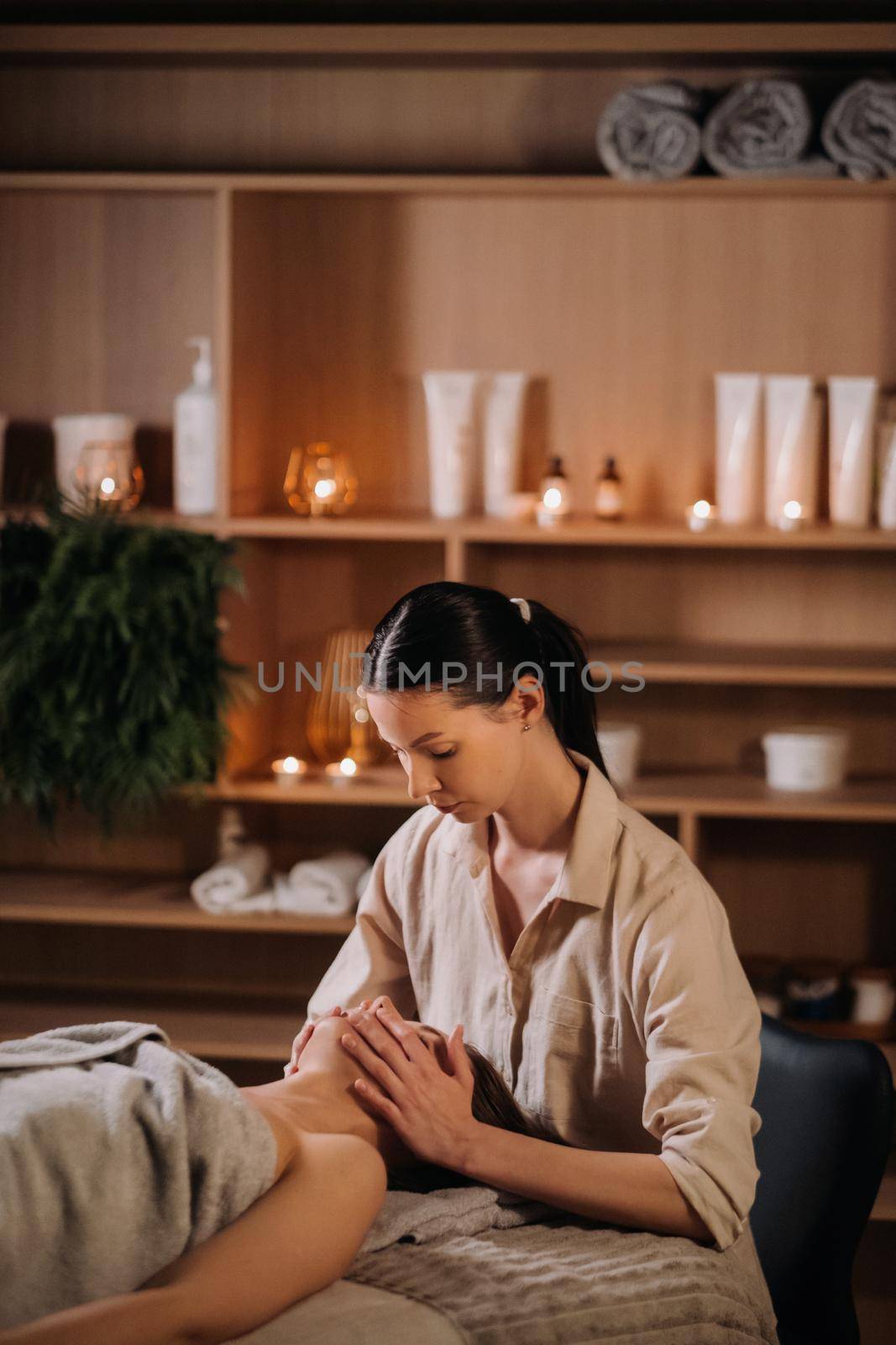 A cosmetologist girl does a facial and neck massage to a girl in the office for skin elasticity.