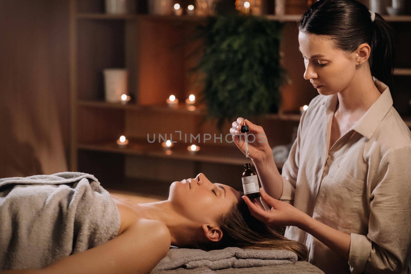 A female cosmetologist holds a pipette with essential oil before aromatherapy and massage to the patient. aromatherapy.