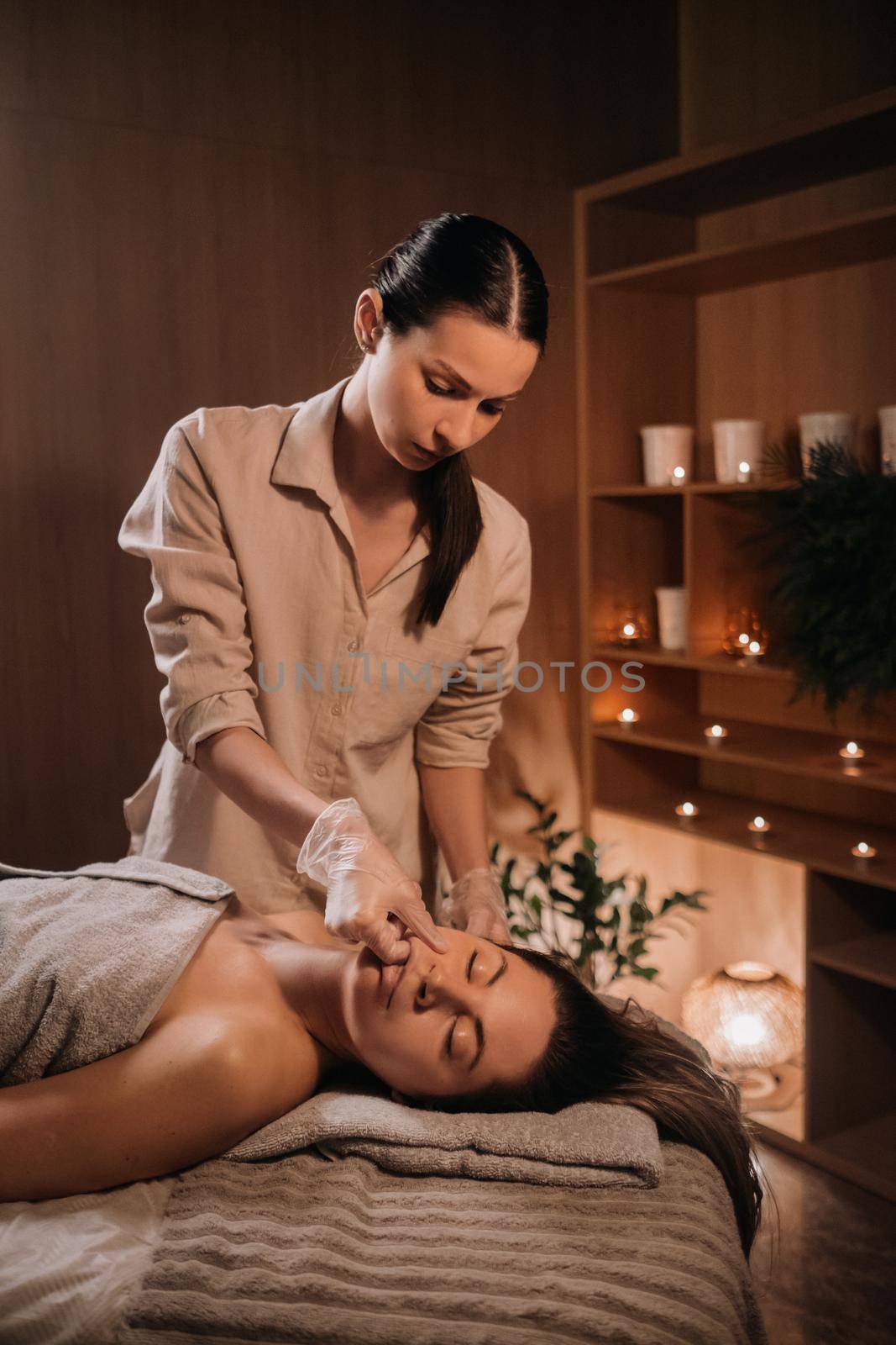 A cosmetologist girl does a facial and neck massage to a girl in the office for skin elasticity by Lobachad